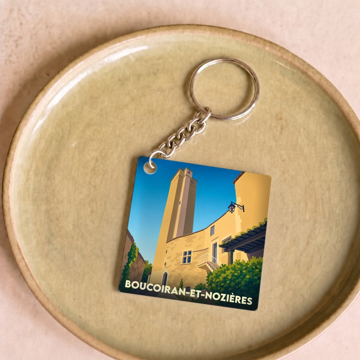 Porte-clés souvenir de la commune de Boucoiran-et-Nozières avec une illustration stylisée de son patrimoine.