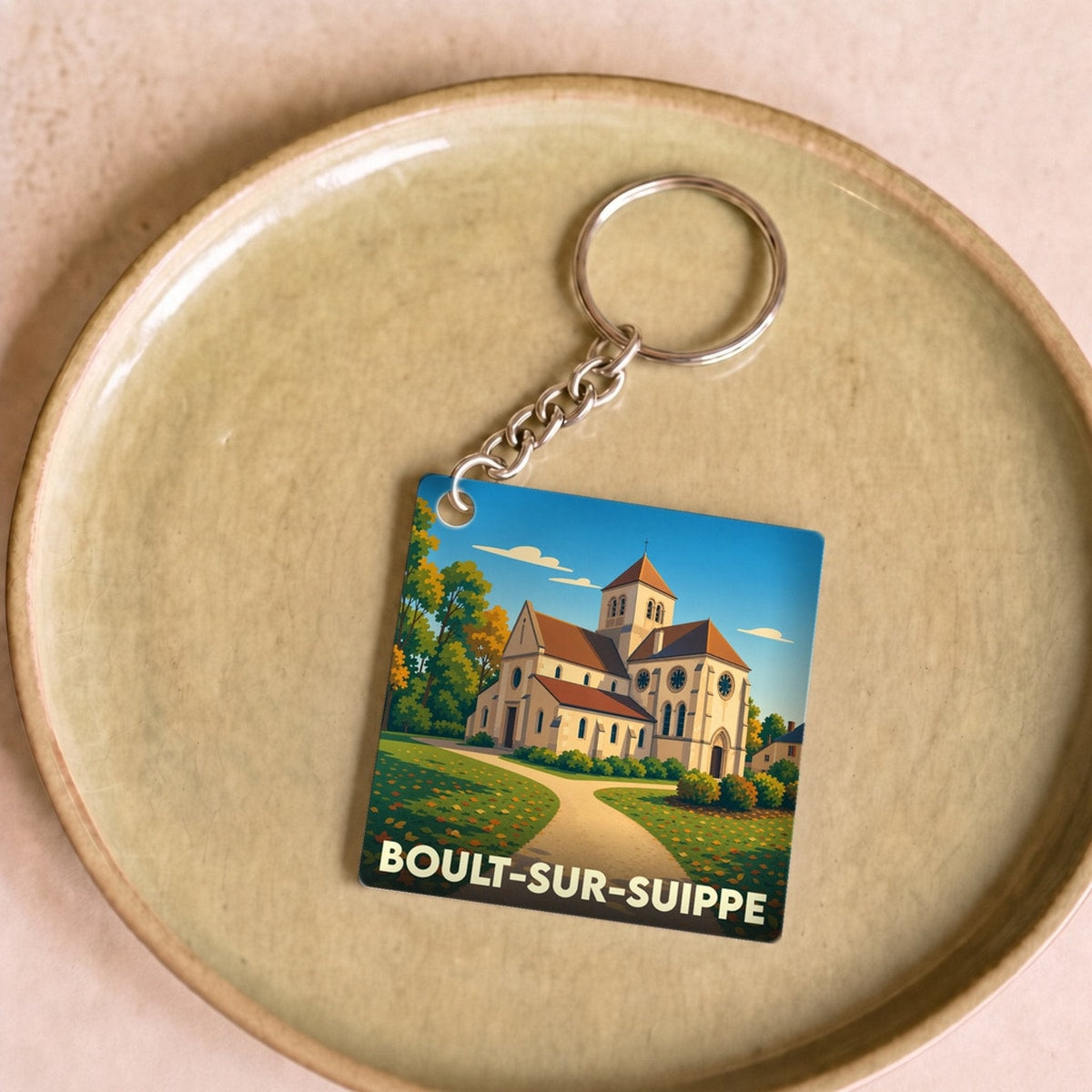 Porte-clés souvenir de la ville de Boult-sur-Suippe avec une illustration stylisée de son église.