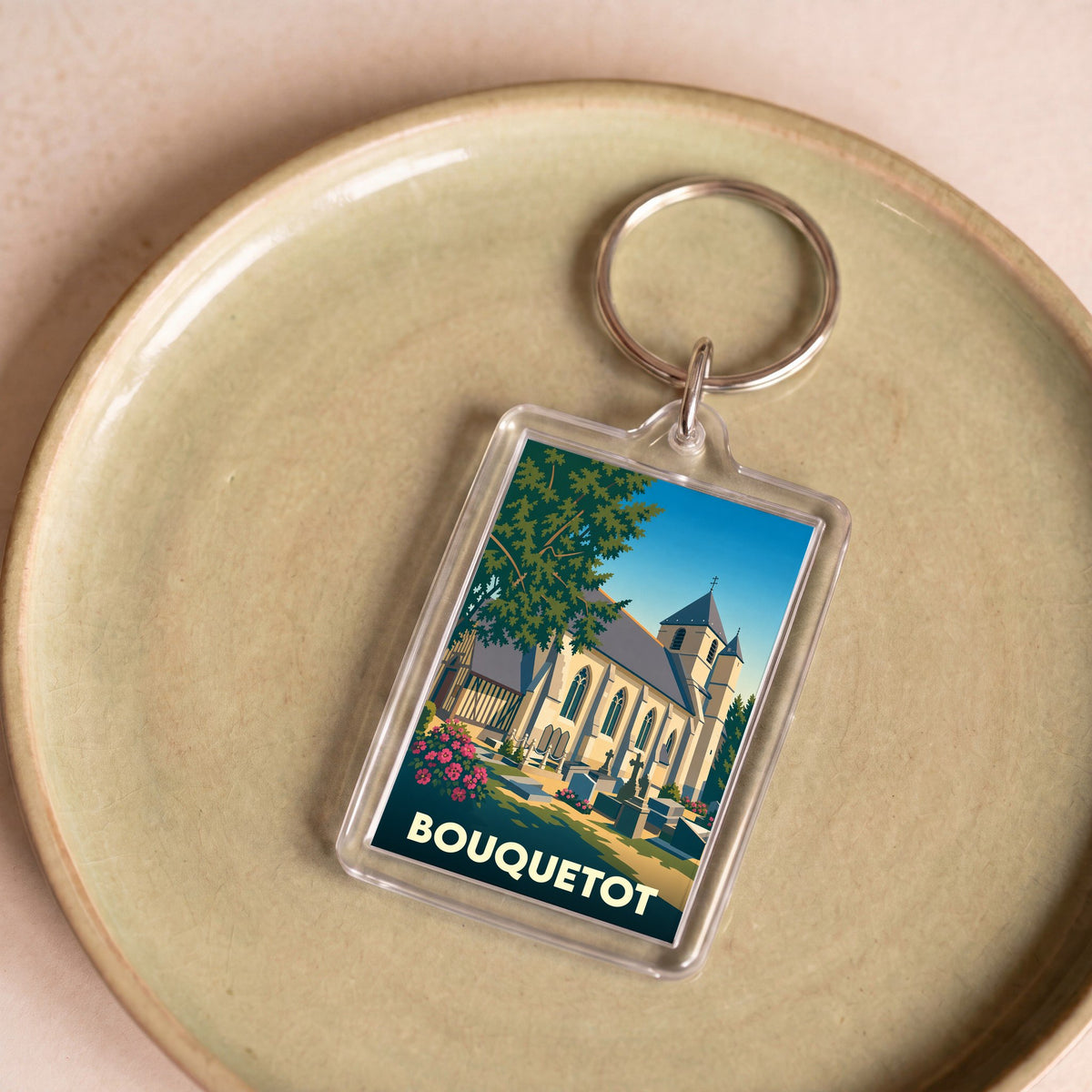 Porte-clés souvenir de la ville de Bouquetot avec une illustration stylisée de son église.