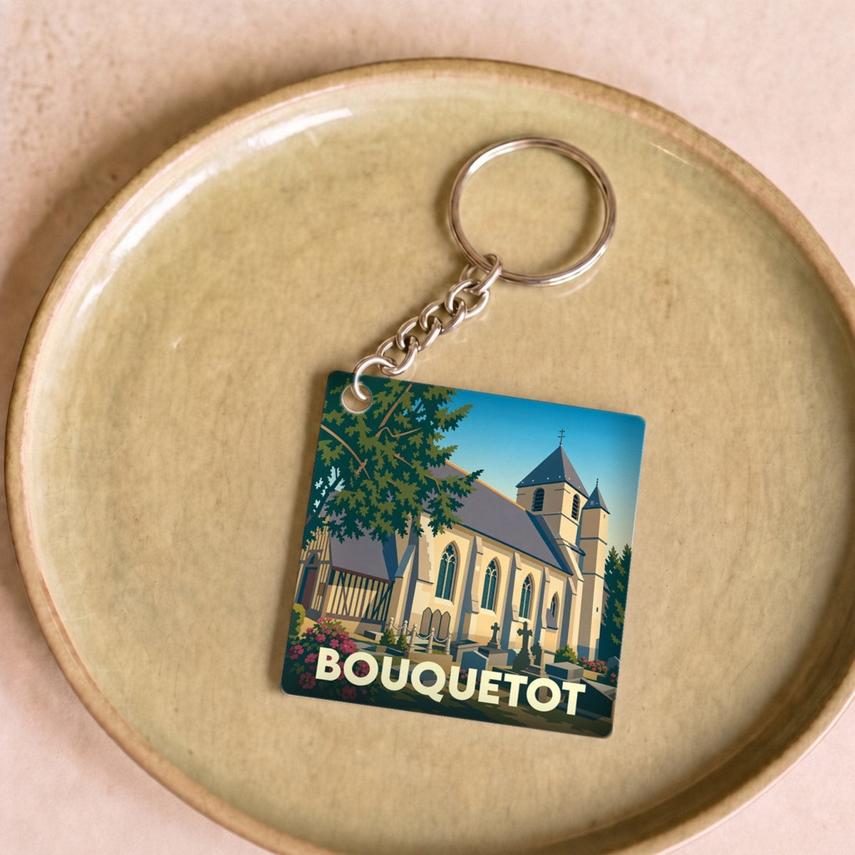 Porte-clés souvenir de la ville de Bouquetot avec une illustration stylisée de son église.