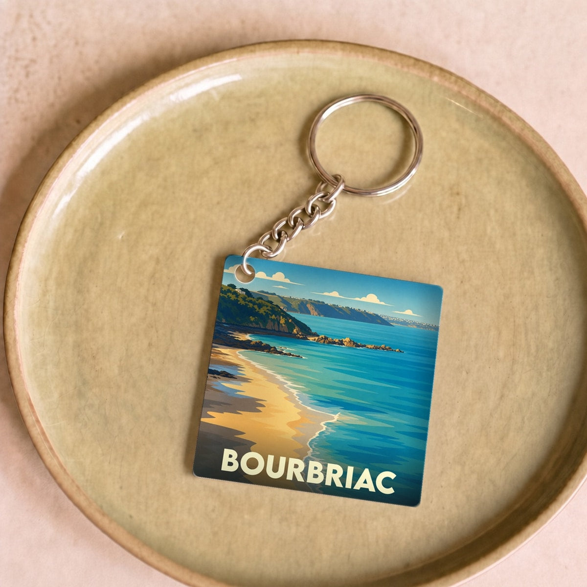 Porte-clés souvenir de la ville de Bourbriac avec une illustration stylisée d'un bord de mer.