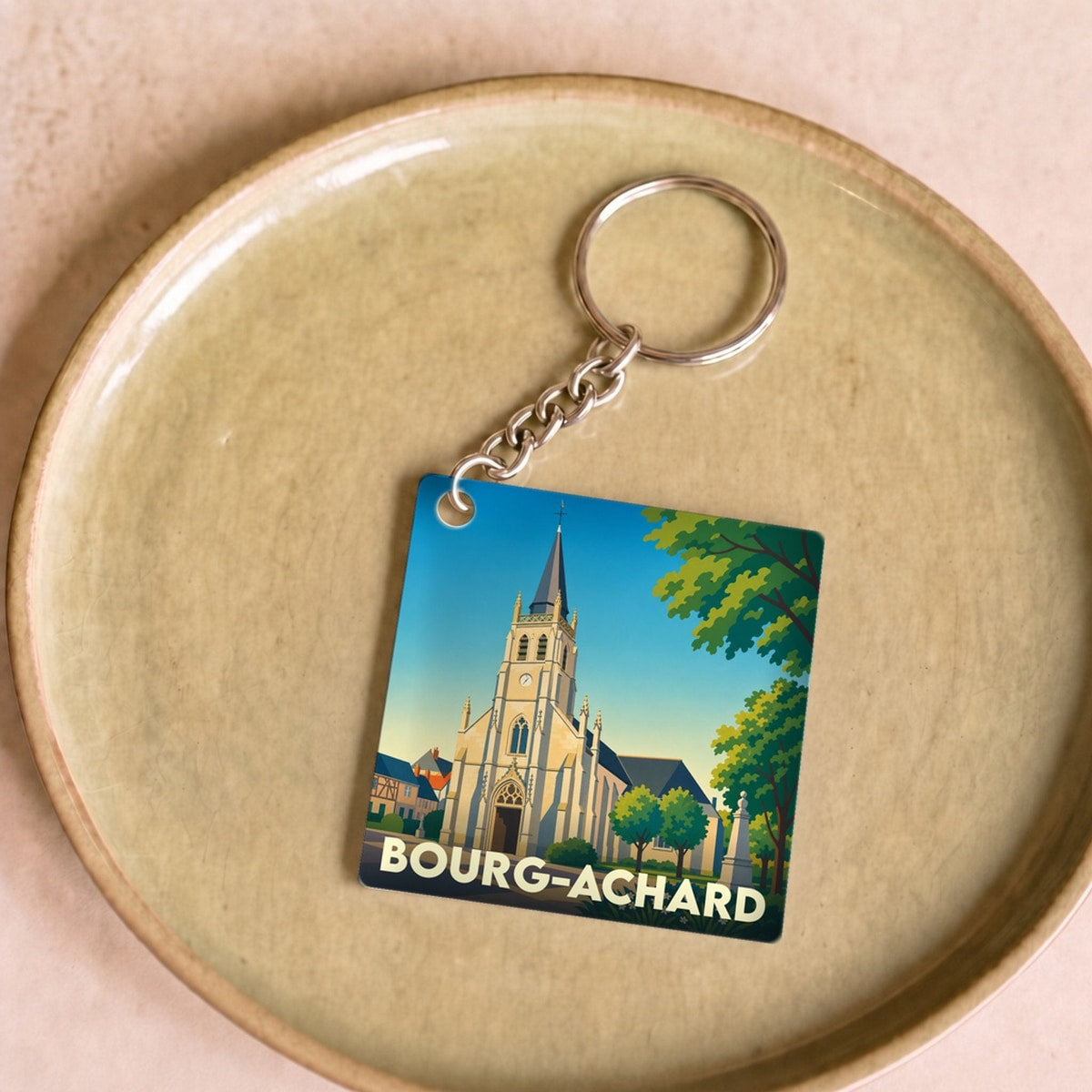 Porte-clés souvenir de la ville de Bourg-Achard avec une illustration stylisée de son église.