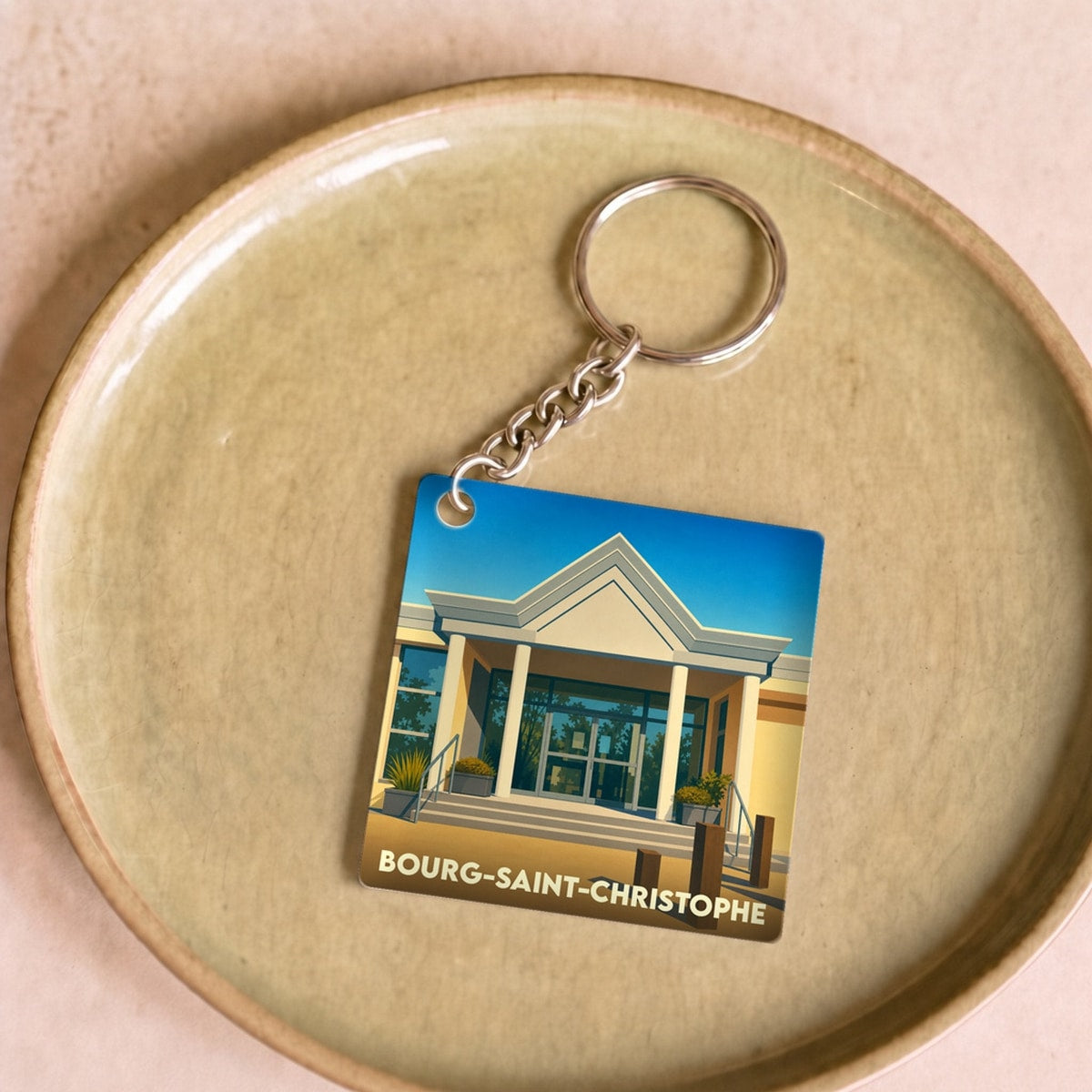Porte-clés souvenir de la ville de Bourg-Saint-Christophe avec une illustration stylisée.