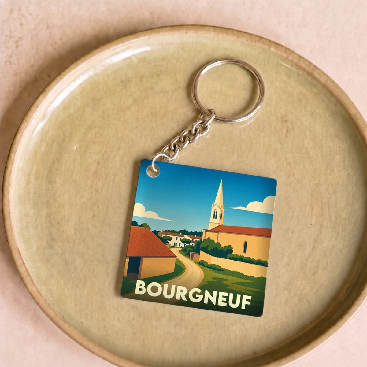 Porte-clés souvenir de la ville de Bourgneuf avec une illustration stylisée d'une église et d'un paysage de campagne.