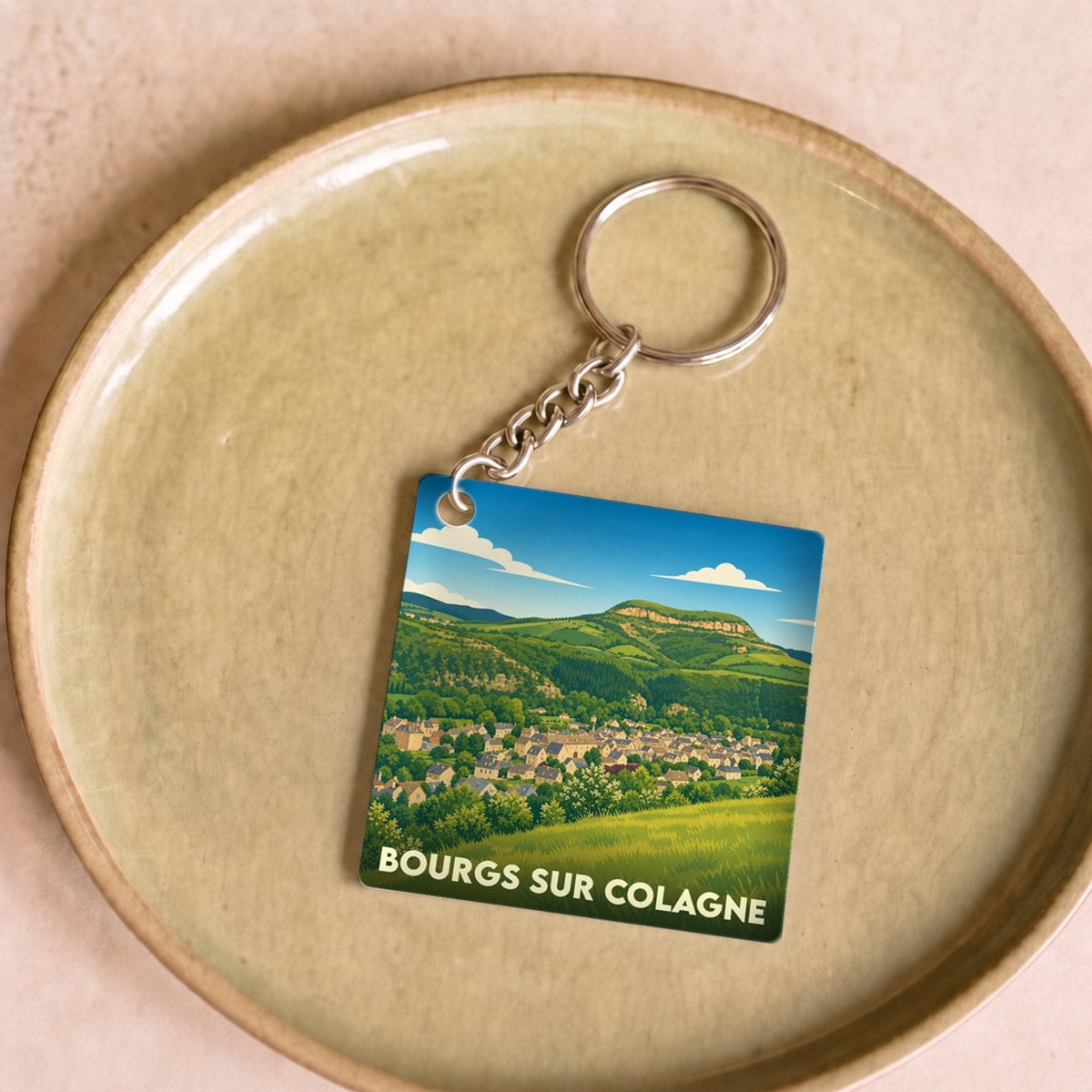 Porte-clés souvenir de la ville de Bourgs sur Colagne avec une illustration paysagère stylisée.