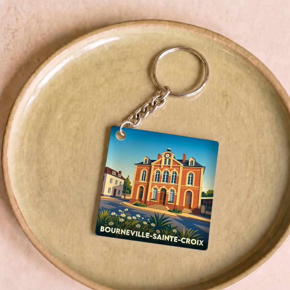Porte-clés souvenir de la ville de Bourneville-Sainte-Croix avec une illustration stylisée de son architecture.