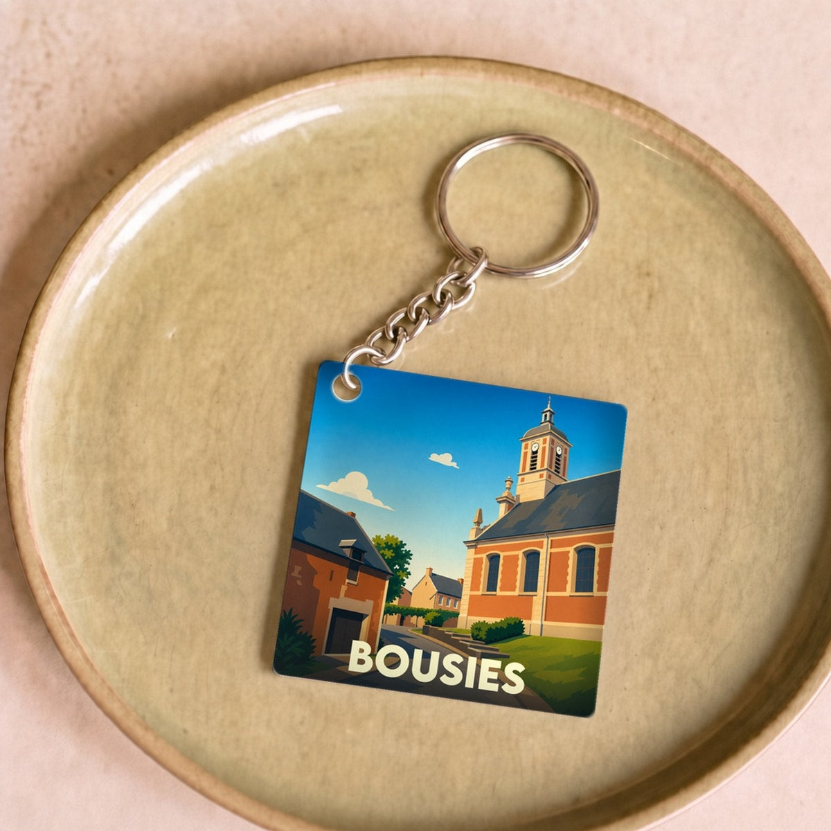 Porte-clés souvenir de la ville de Bousies avec une illustration stylisée de son église.