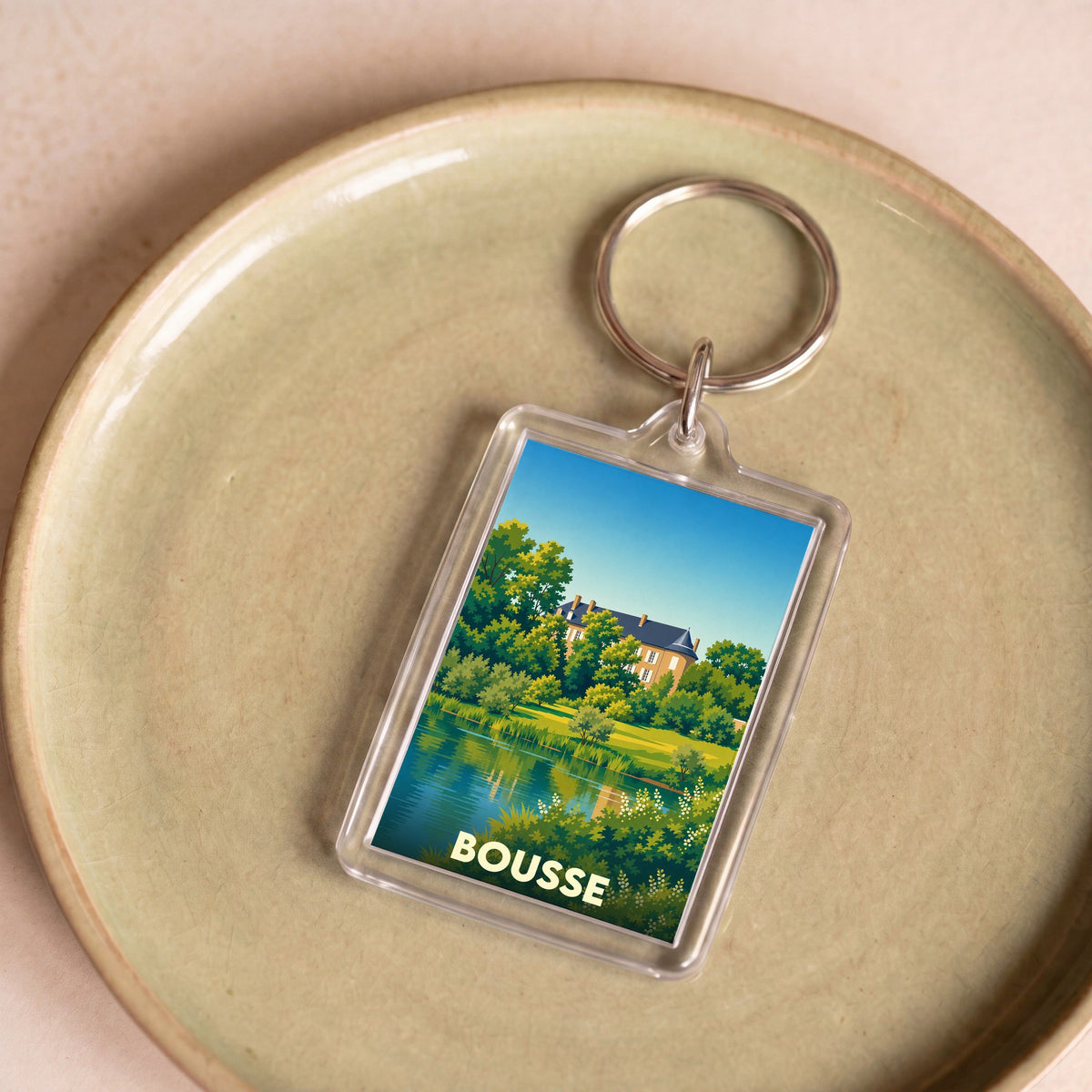 Porte-clés souvenir de la ville de Bousse avec une illustration stylisée d'un château au bord de l'eau.
