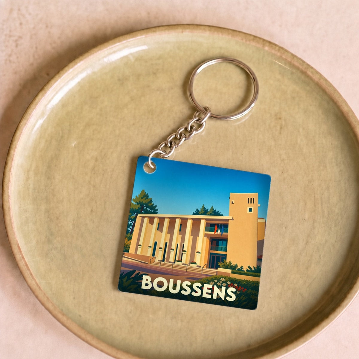 Porte-clés souvenir de la ville de Boussens avec une illustration stylisée.