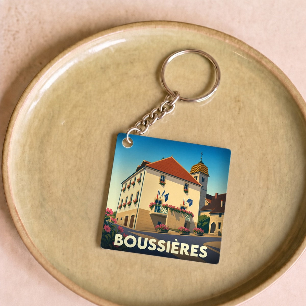 Porte-clés souvenir de la ville de Boussières avec une illustration stylisée.