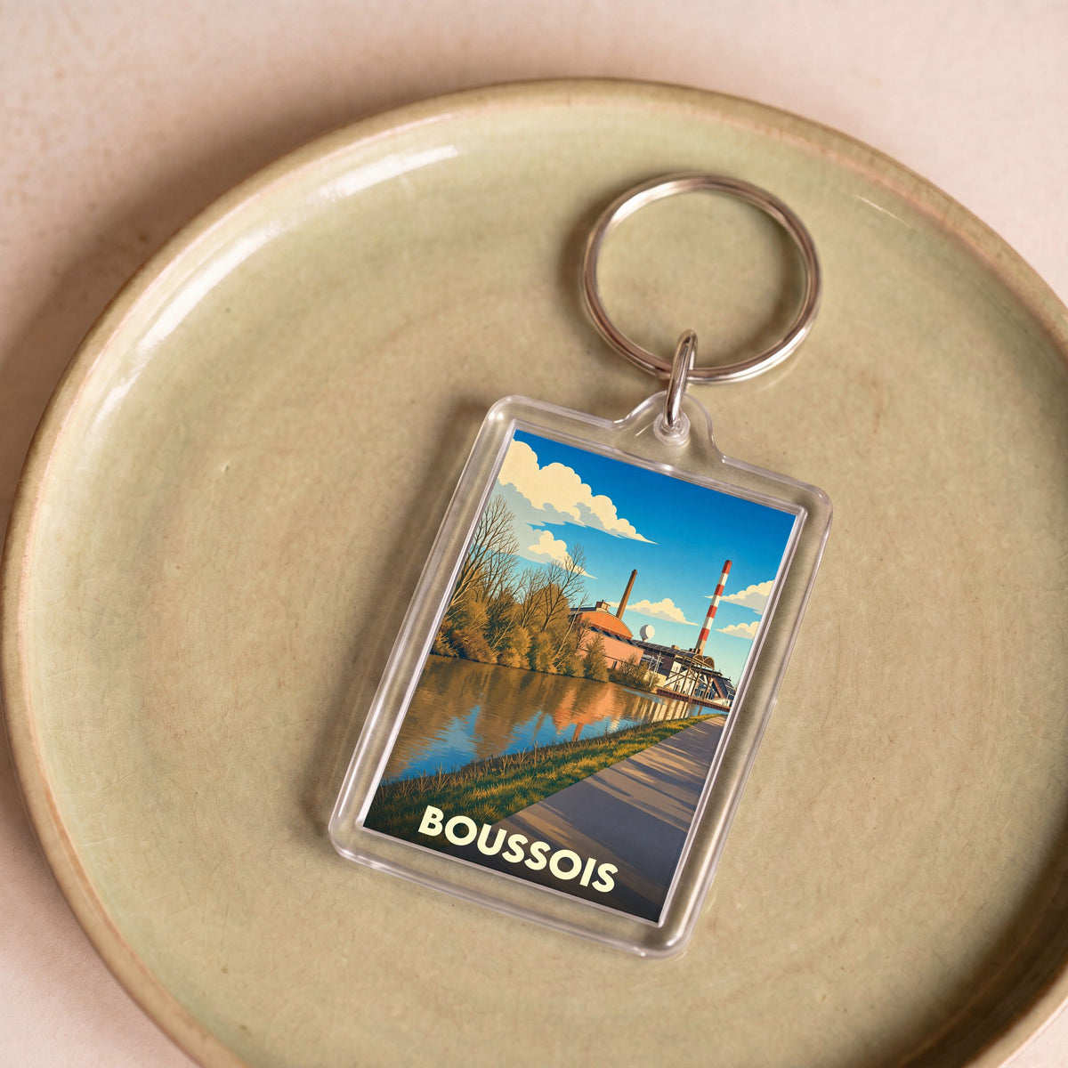 Porte-clés souvenir de la ville de Boussois avec une illustration stylisée de son paysage industriel au bord de l'eau.