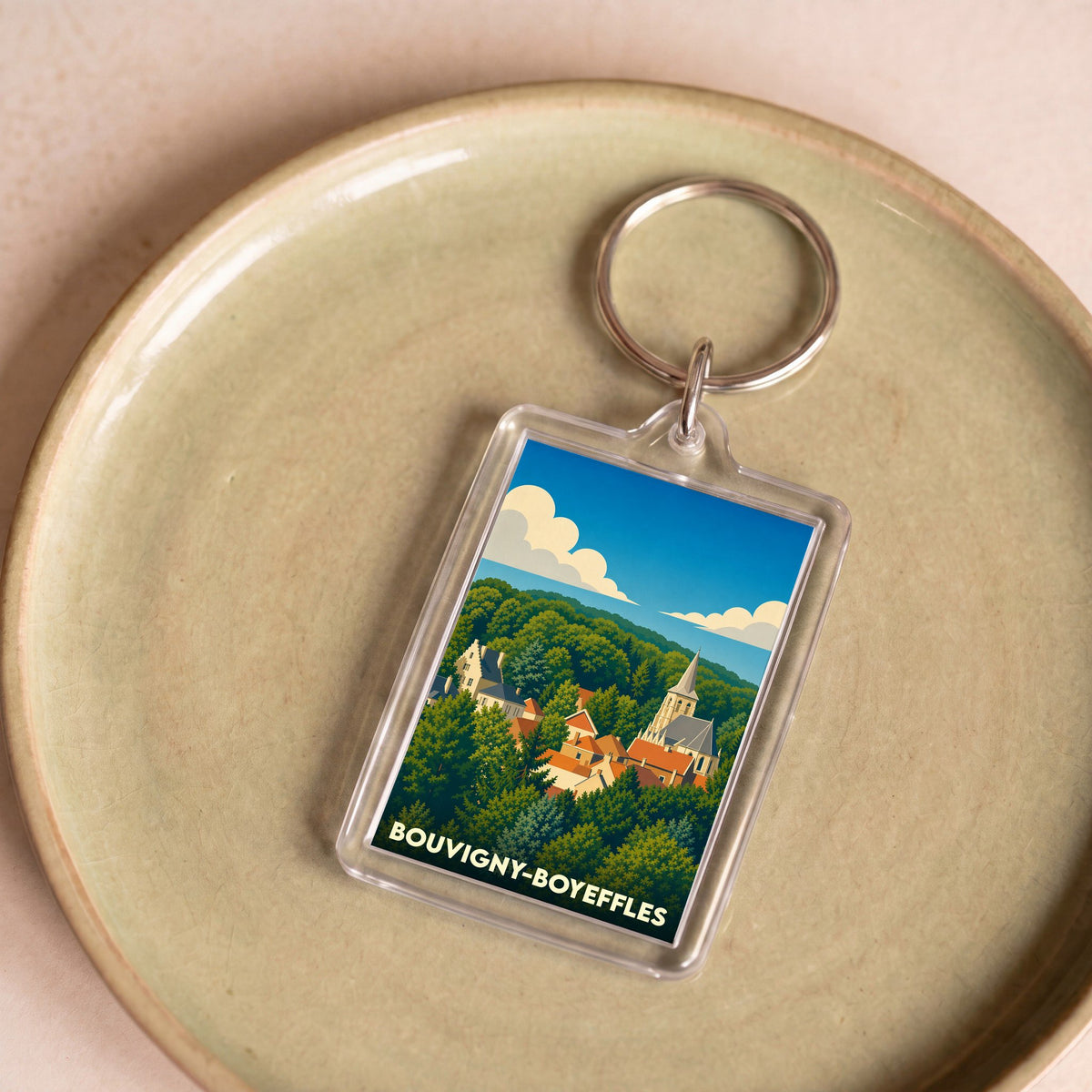 Porte-clés souvenir de la ville de Bouvigny-Boyeffles avec une illustration stylisée de son paysage urbain niché dans la verdure.