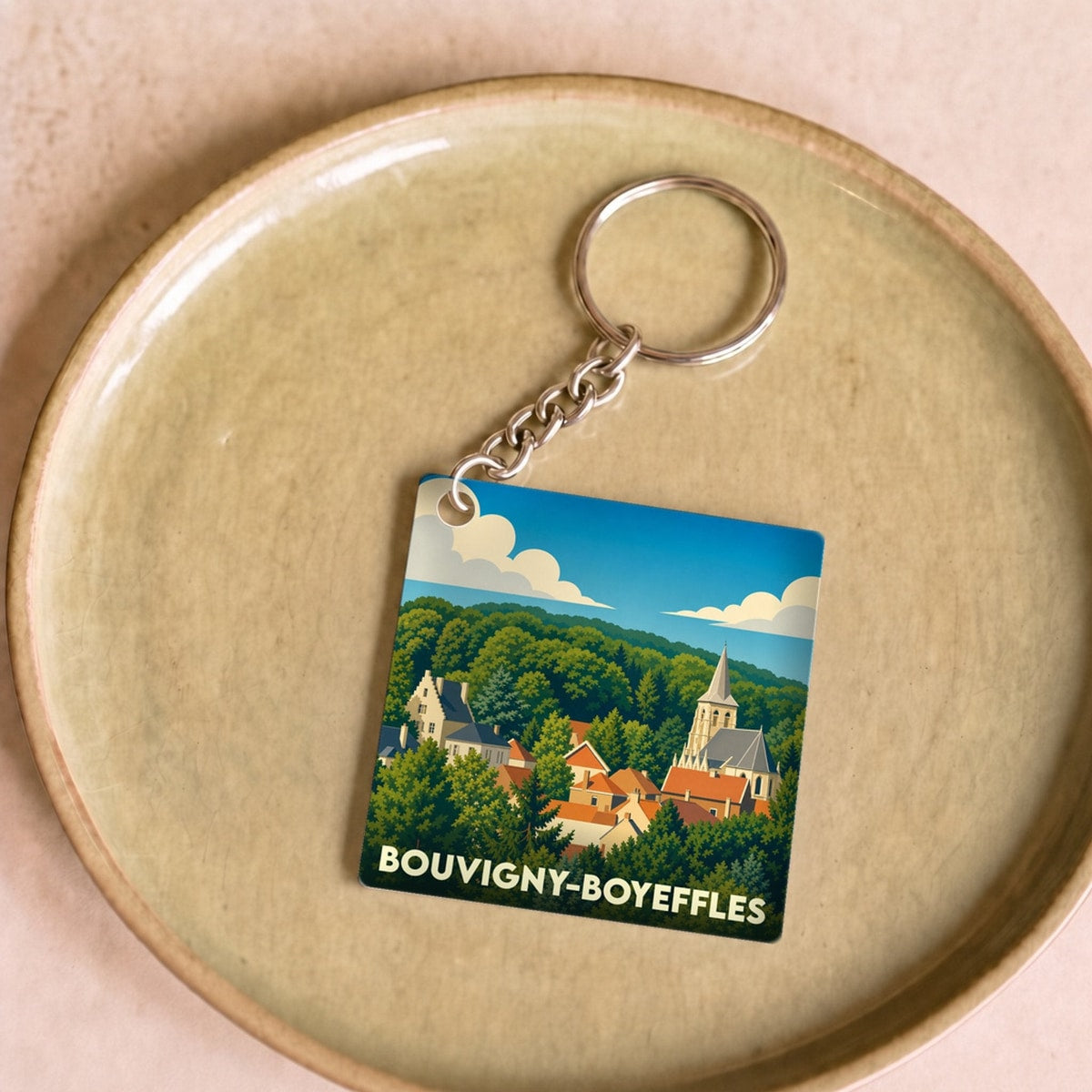 Porte-clés souvenir de la ville de Bouvigny-Boyeffles avec une illustration stylisée de son paysage urbain niché dans la verdure.