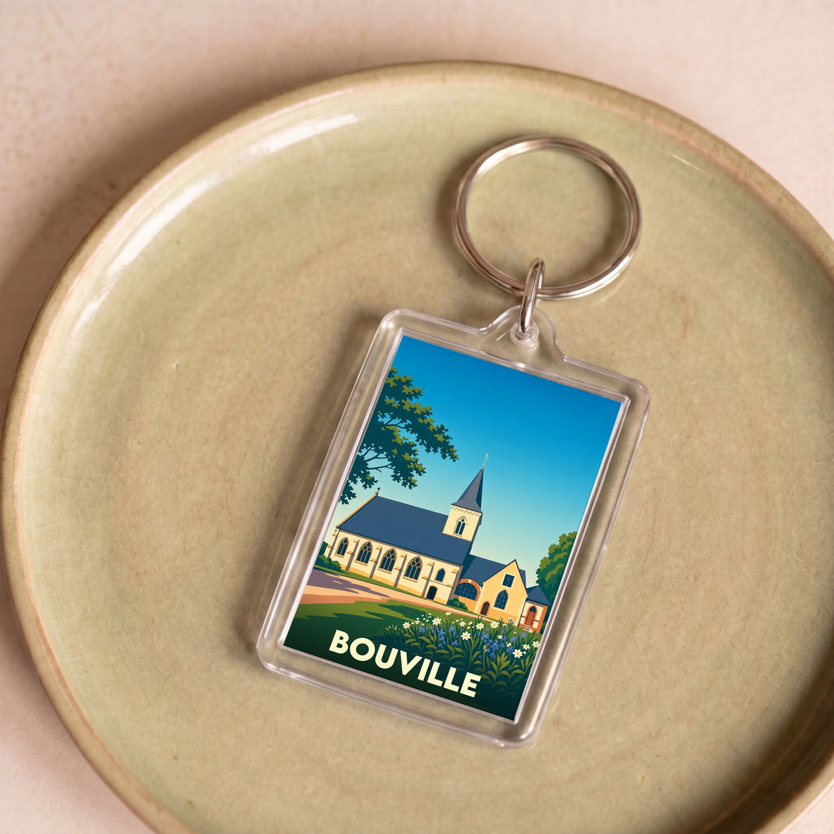 Porte-clés souvenir de la ville de Bouville avec une illustration stylisée d'une église sous un ciel bleu.