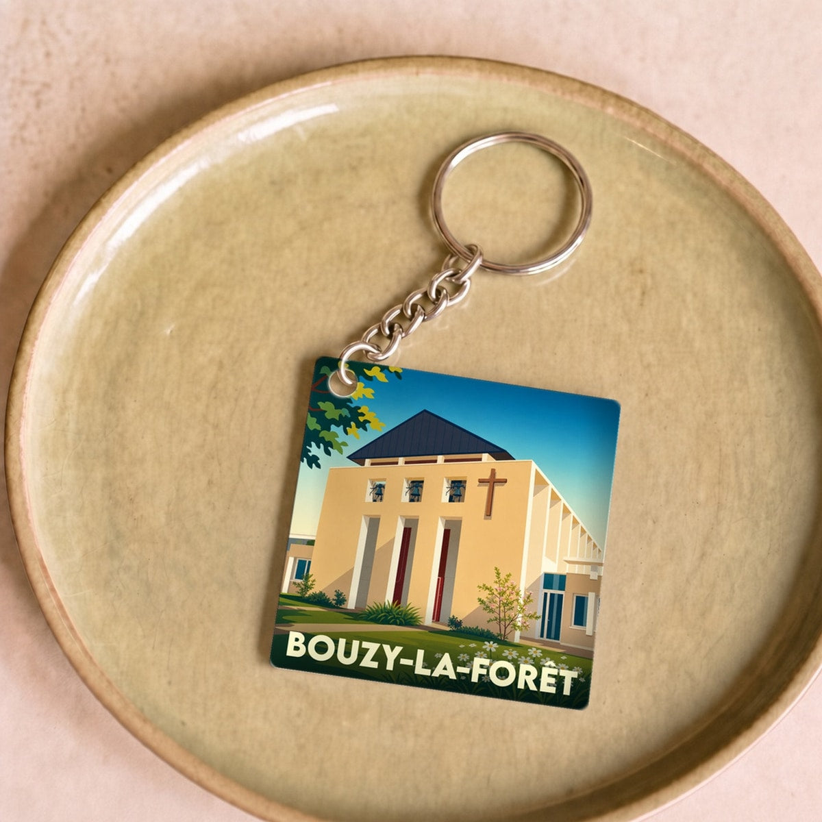 Porte-clés souvenir de la ville de Bouzy-la-Forêt avec une illustration stylisée de son église.