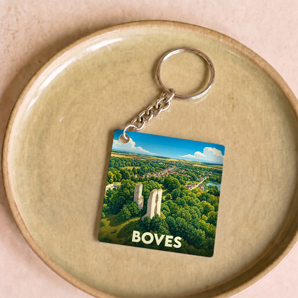 Porte-clés souvenir de la ville de Boves avec une illustration stylisée de son château et de sa forêt.