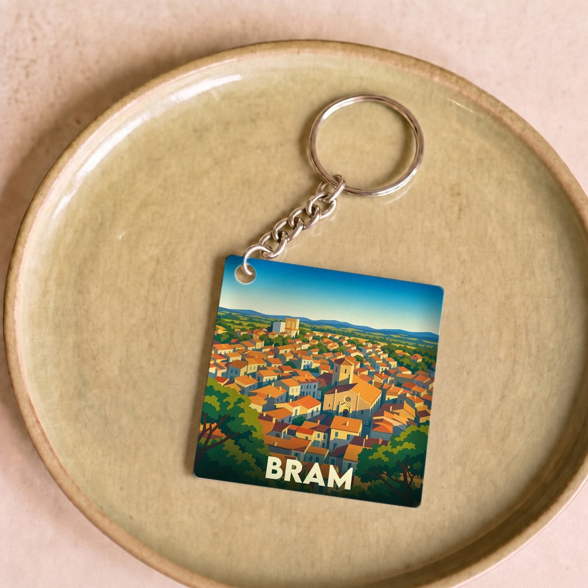 Porte-clés souvenir de la ville de Bram avec une illustration stylisée de ses toits orangés.