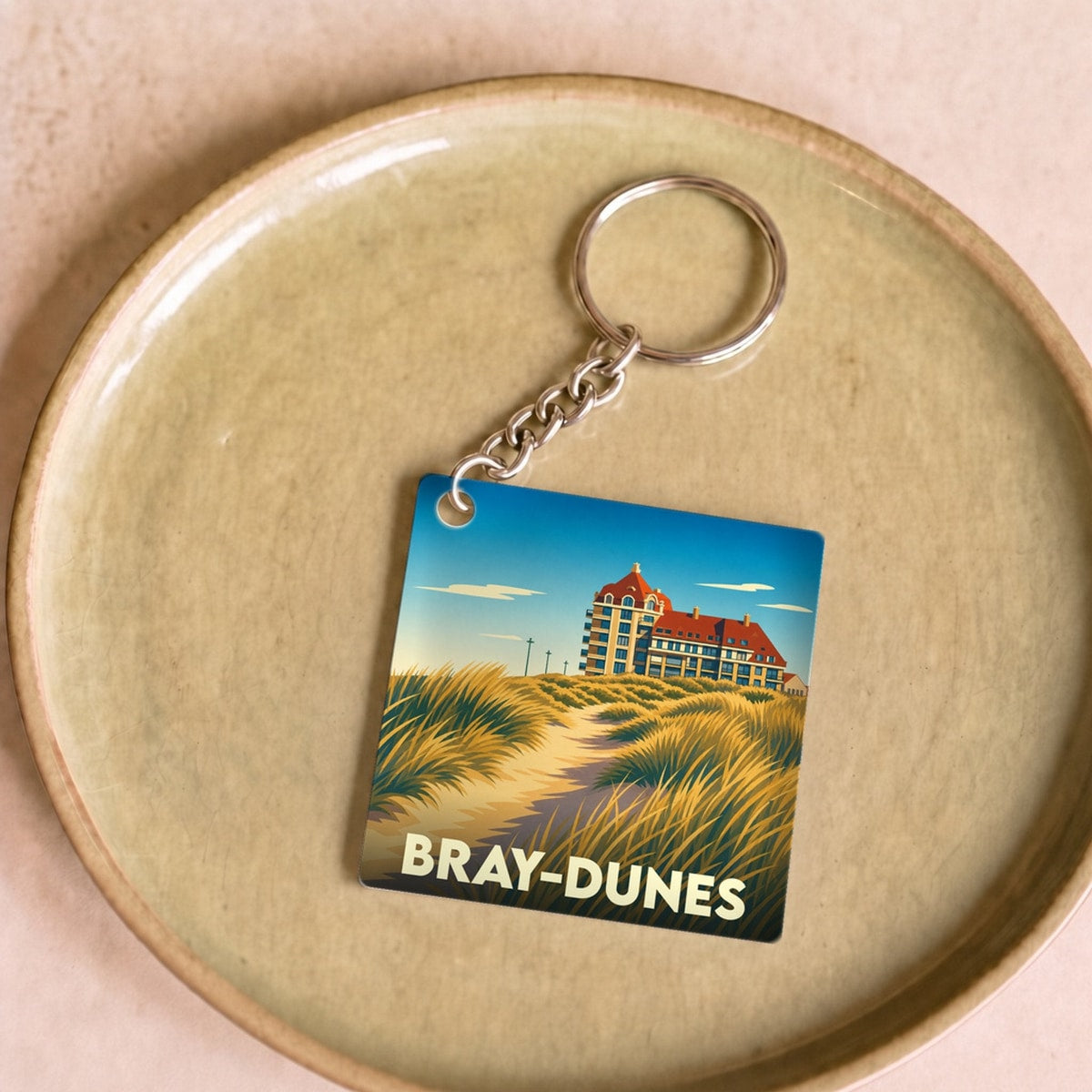 Porte-clés souvenir de la ville de Bray-Dunes avec une illustration stylisée de ses dunes et de son architecture.