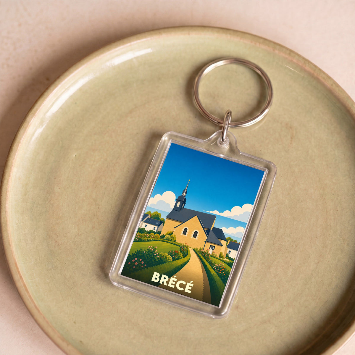 Porte-clés souvenir de la ville de Brécé avec une illustration stylisée de son église.