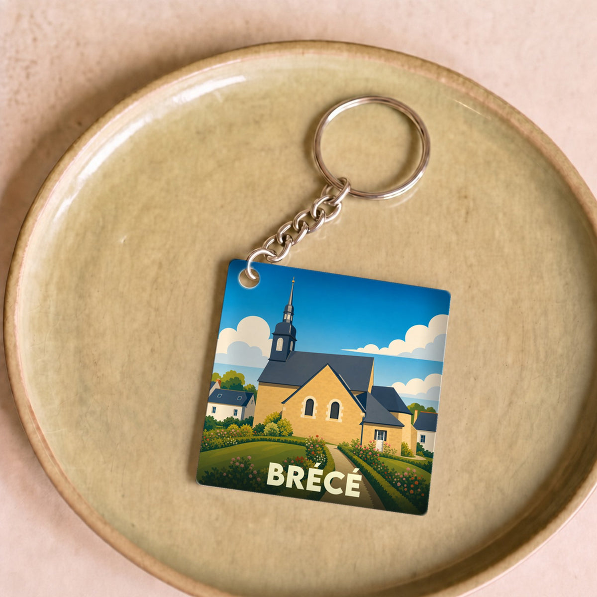 Porte-clés souvenir de la ville de Brécé avec une illustration stylisée de son église.