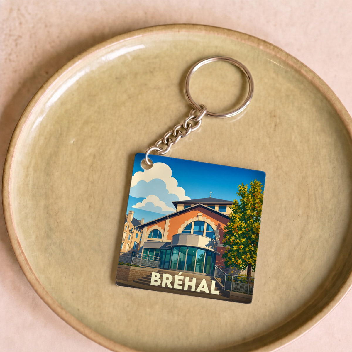 Porte-clés souvenir de la ville de Bréhal avec une illustration stylisée.