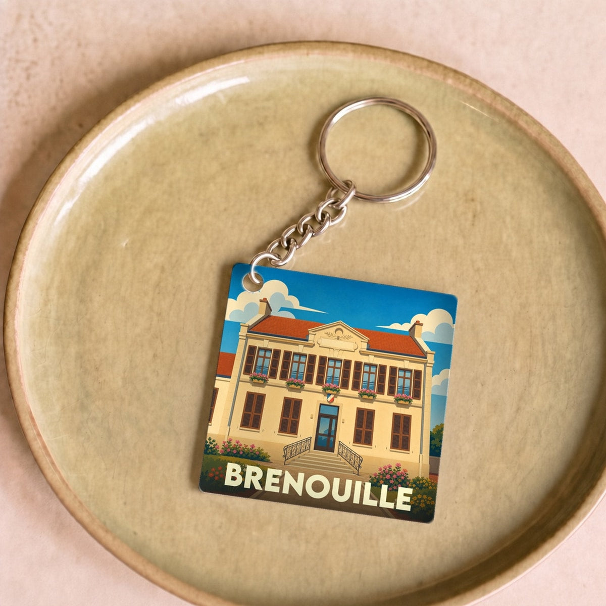 Porte-clés souvenir de la ville de Brenouille avec une illustration stylisée de sa mairie.