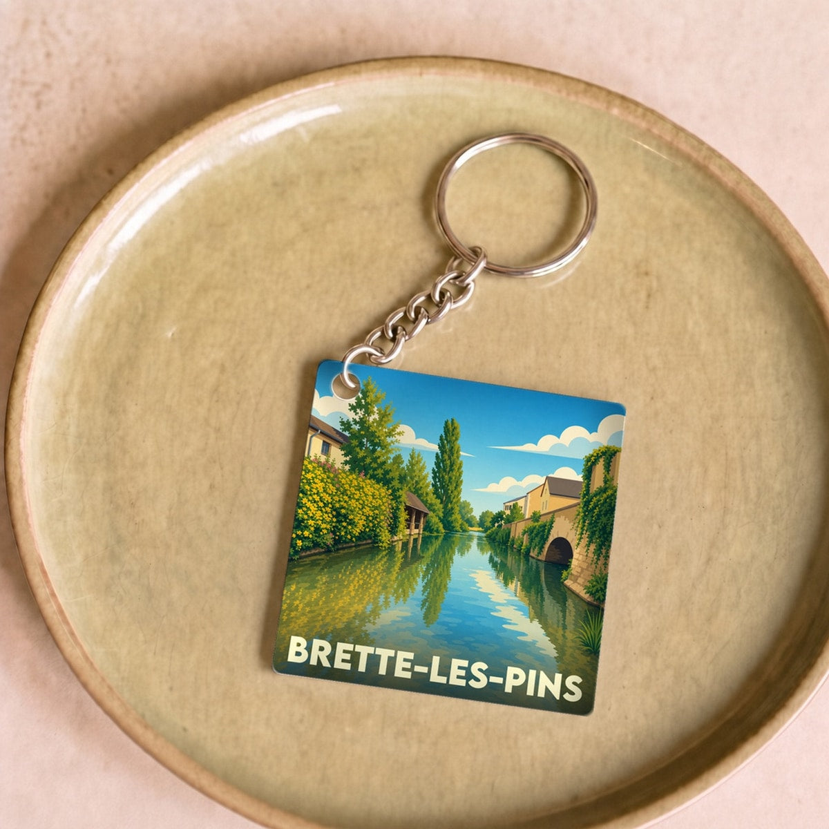 Porte-clés souvenir de la ville de Brette-les-Pins avec une illustration stylisée d'un canal.