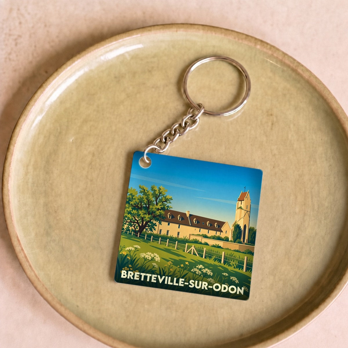Porte-clés souvenir de la ville de Bretteville-sur-Odon avec une illustration stylisée.
