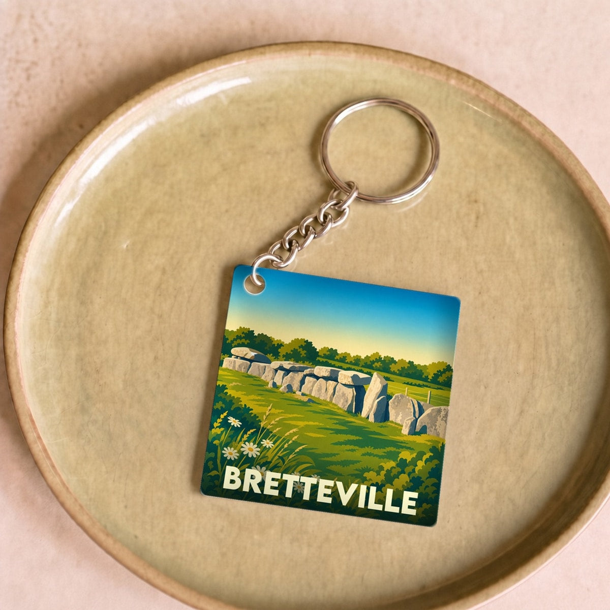 Porte-clés souvenir de la ville de Bretteville avec une illustration stylisée d'un monument mégalithique.