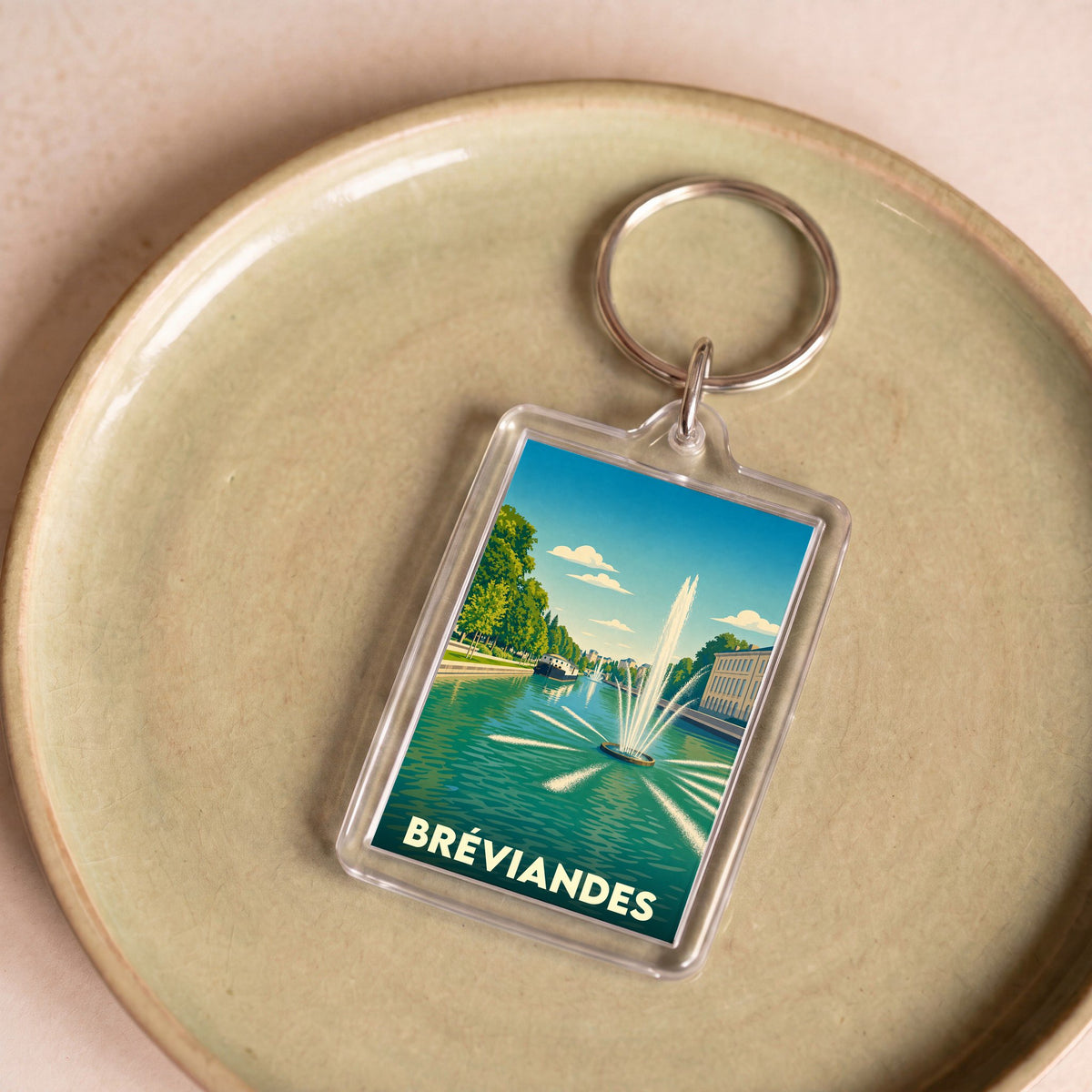 Porte-clés souvenir de la ville de Bréviandes avec une illustration stylisée d'un jet d'eau sur un canal.