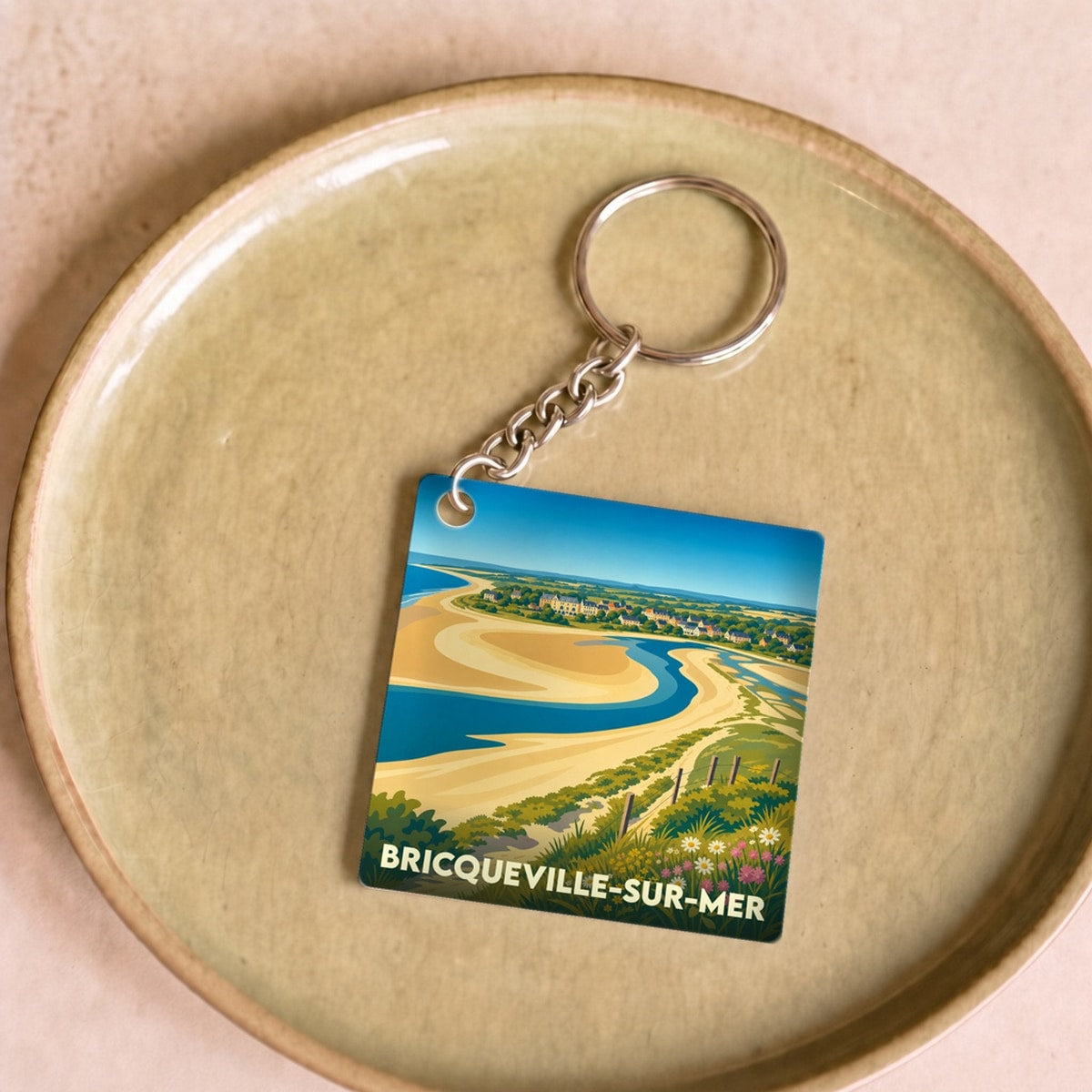 Porte-clés souvenir de la ville de Bricqueville-sur-Mer avec une illustration stylisée d'un paysage côtier.