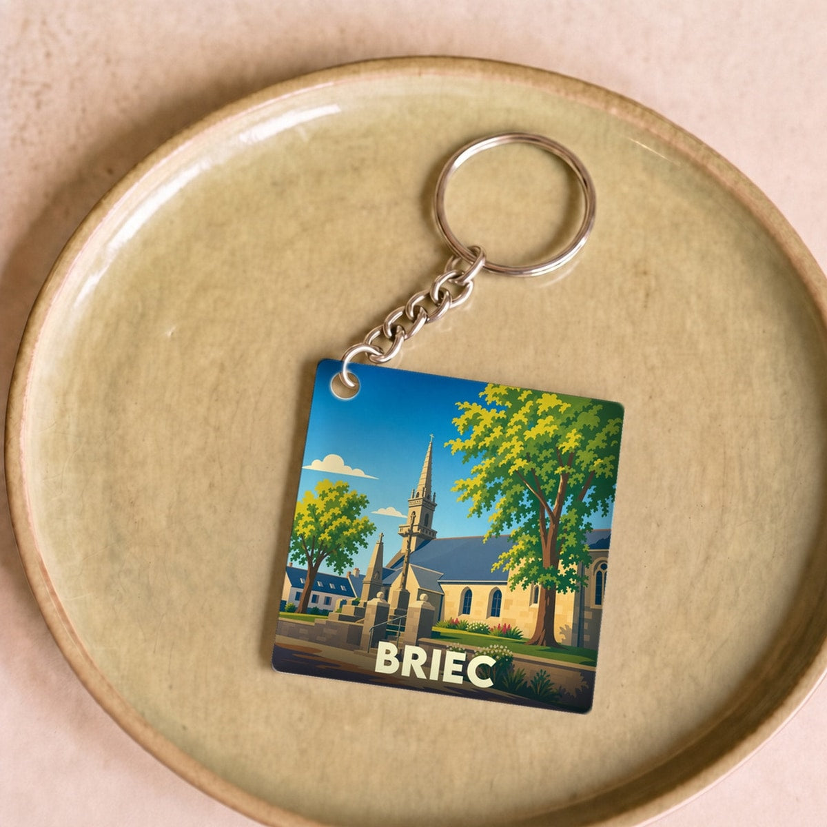 Porte-clés souvenir de la ville de Briec avec une illustration stylisée d'une église et de grands arbres.
