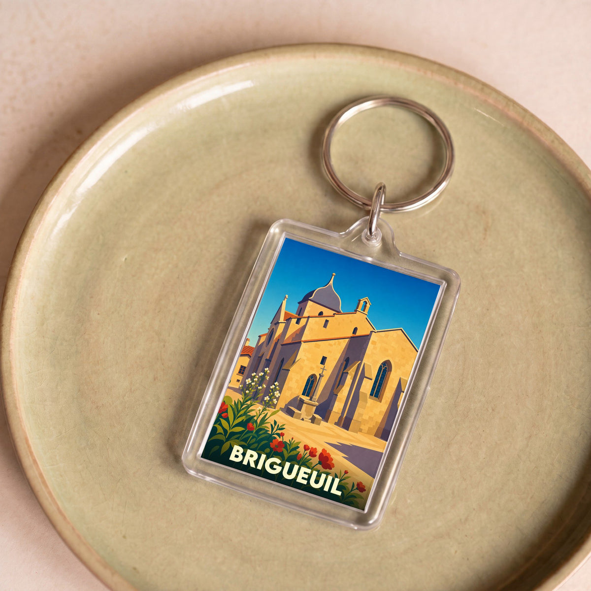 Porte-clés souvenir de la ville de Brigueuil avec une illustration stylisée de son église.