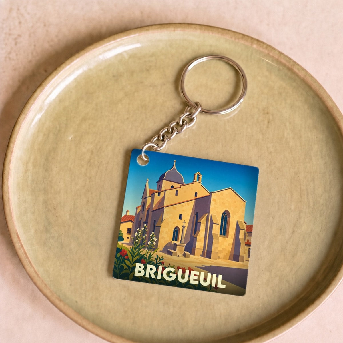 Porte-clés souvenir de la ville de Brigueuil avec une illustration stylisée de son église.