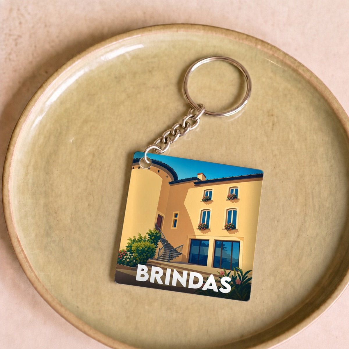 Porte-clés souvenir de la ville de Brindas avec une illustration stylisée d'un bâtiment local.
