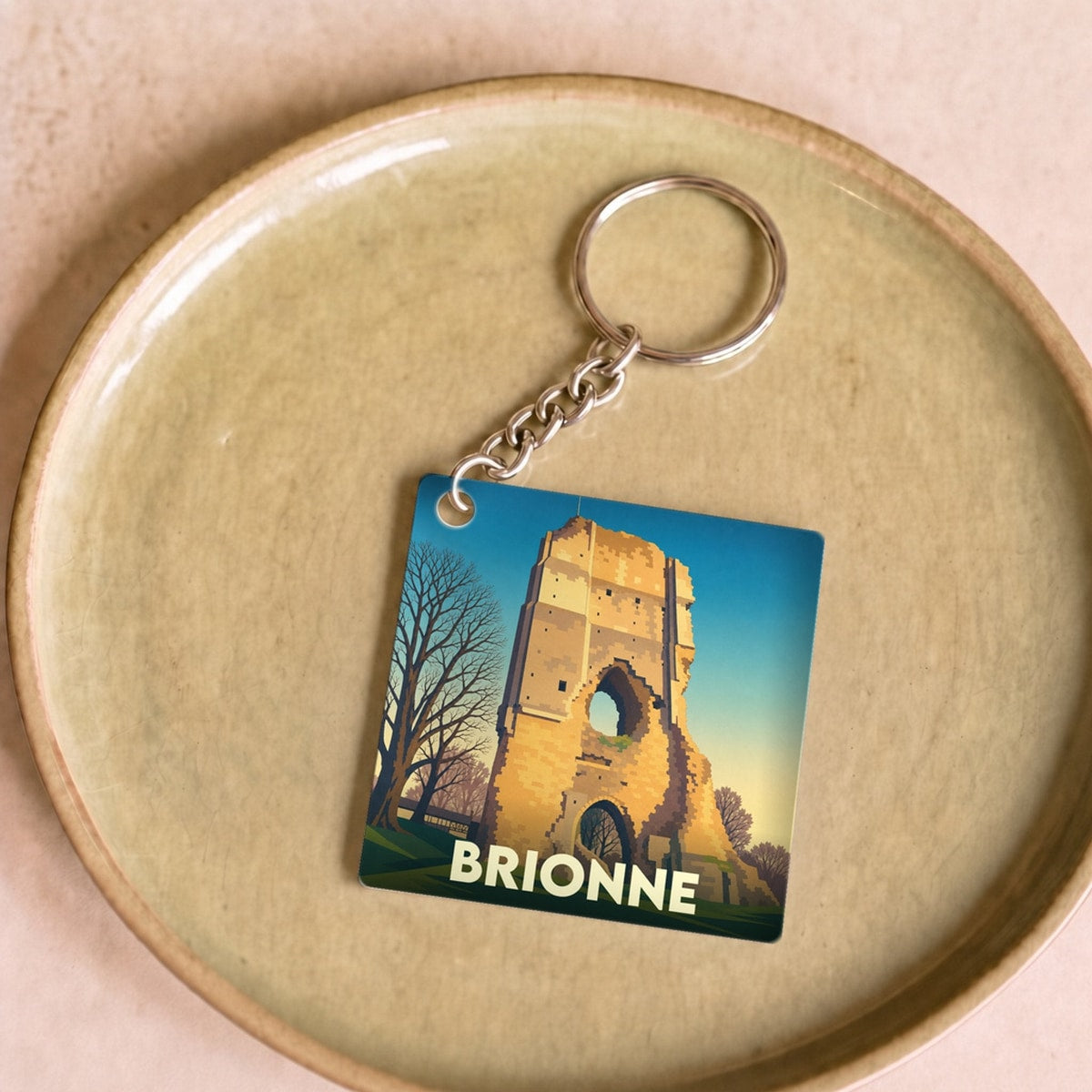 Porte-clés souvenir de la ville de Brionne avec une illustration stylisée de son donjon historique.
