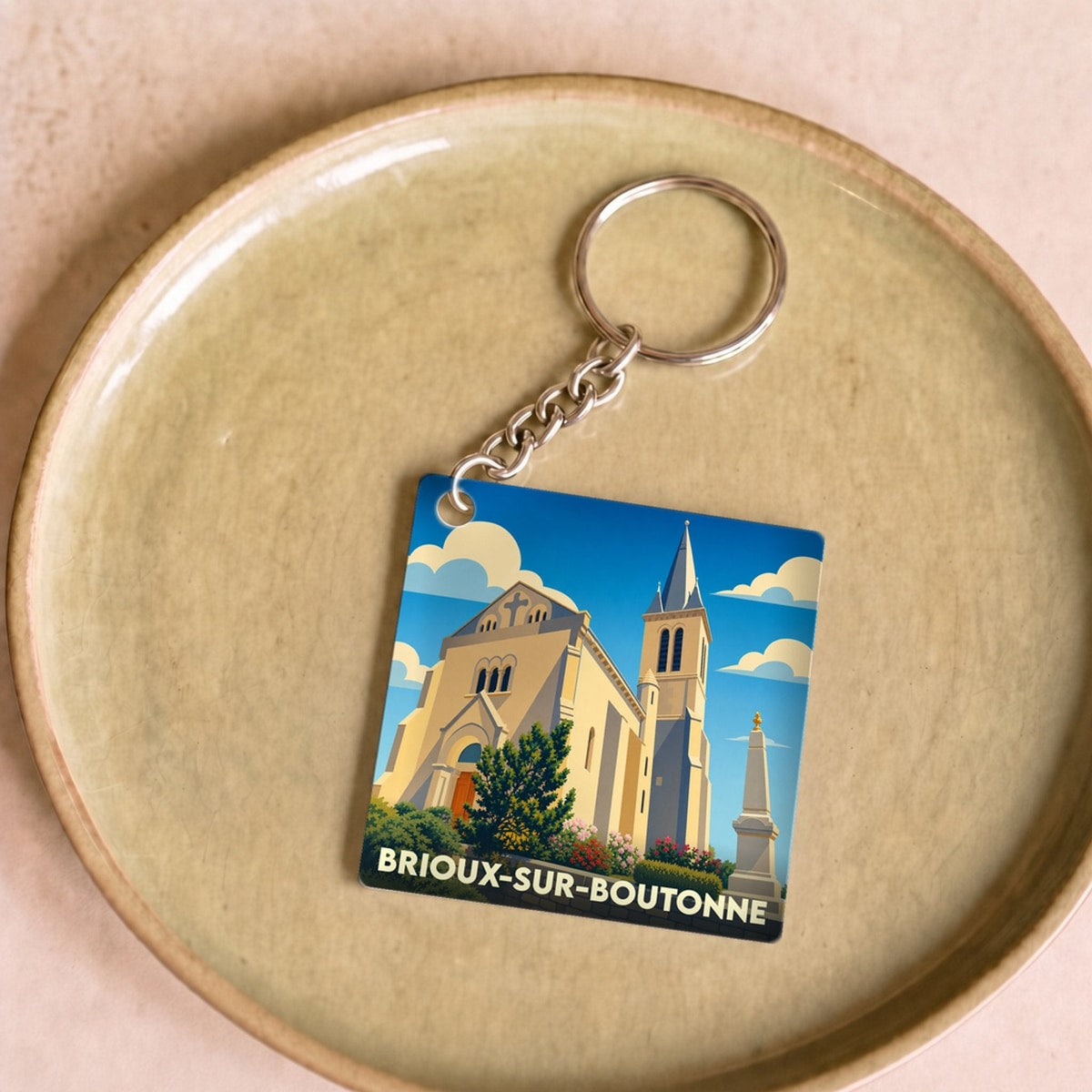 Porte-clés souvenir de la ville de Brioux-sur-Boutonne avec une illustration stylisée de son église.