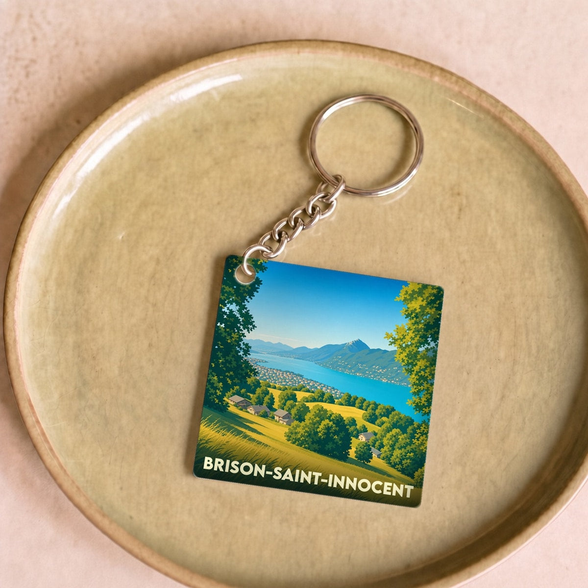 Porte-clés souvenir de la ville de Brison-Saint-Innocent avec une illustration stylisée du lac et des montagnes.