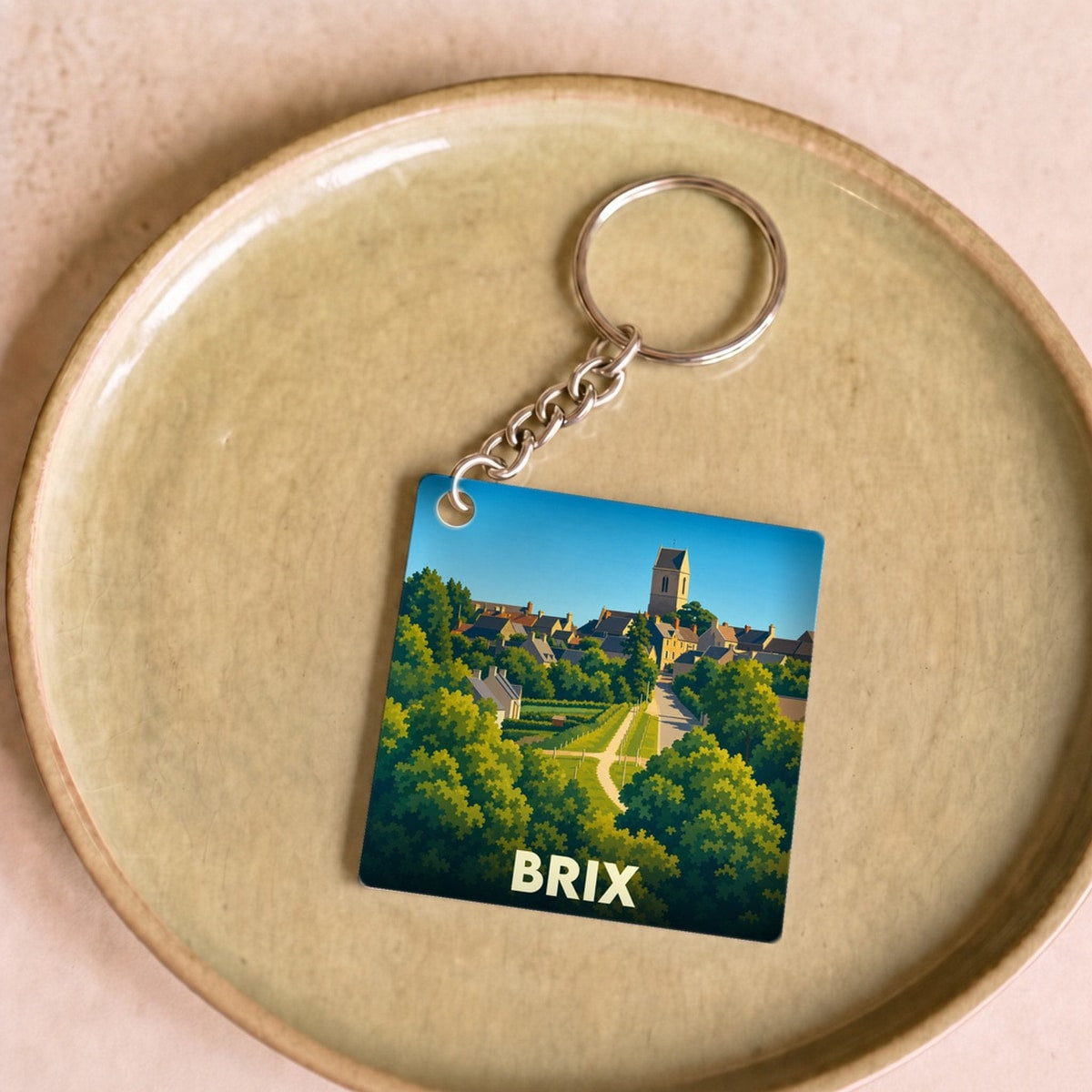 Porte-clés souvenir de la ville de Brix avec une illustration stylisée d'un paysage urbain verdoyant.