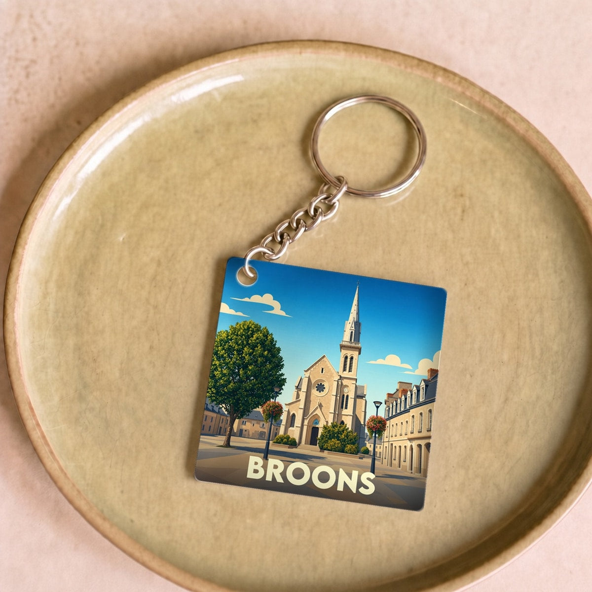 Porte-clés souvenir de la ville de Broons avec une illustration stylisée de son église.