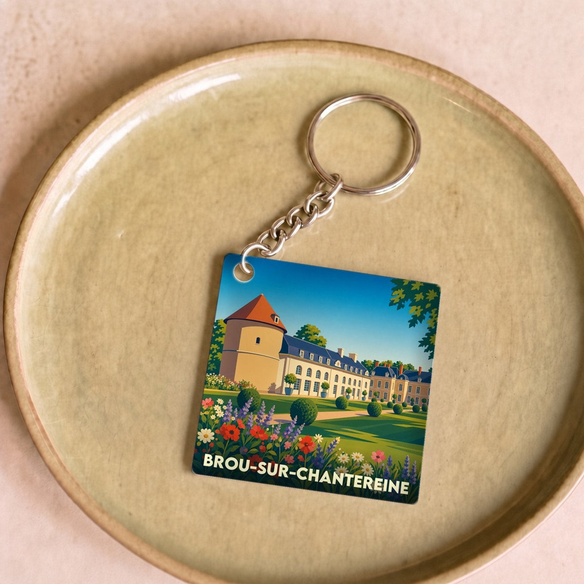 Porte-clés souvenir de la ville de Brou-sur-Chantereine avec une illustration stylisée de son château et de ses jardins.