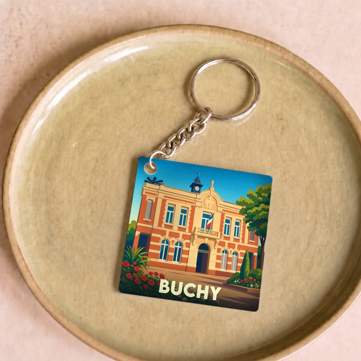 Porte-clés souvenir de la ville de Buchy avec une illustration stylisée de son hôtel de ville.
