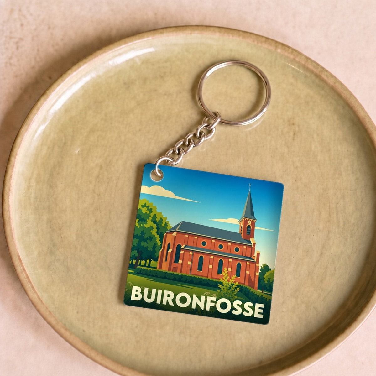Porte-clés souvenir de la ville de Buironfosse avec une illustration stylisée d'une église en briques.
