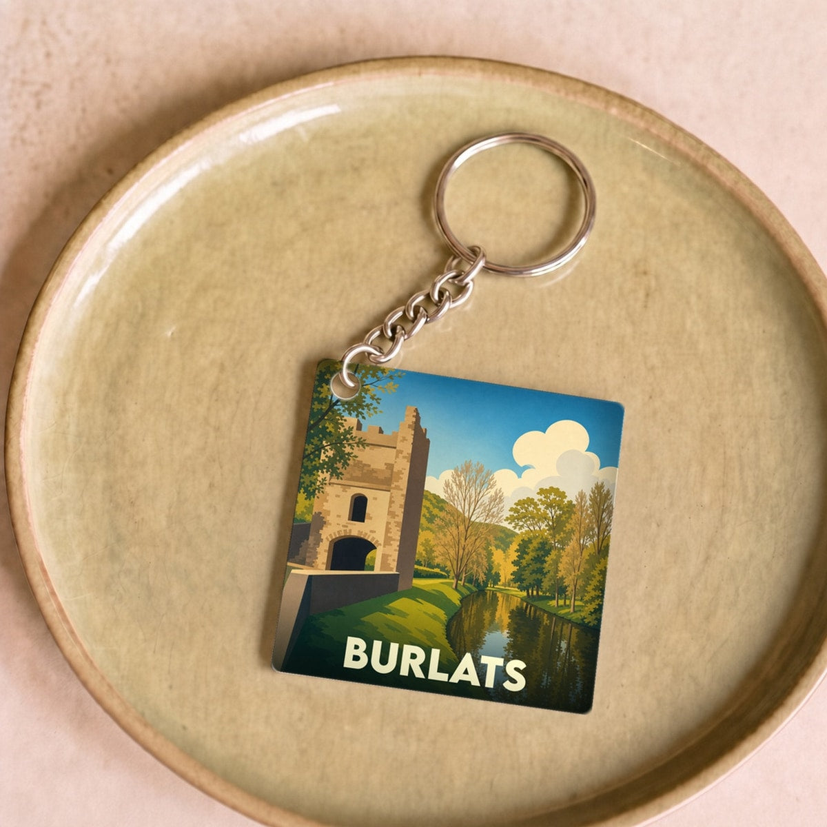 Porte-clés souvenir de la ville de Burlats avec une illustration stylisée d'un monument historique au bord de l'eau.