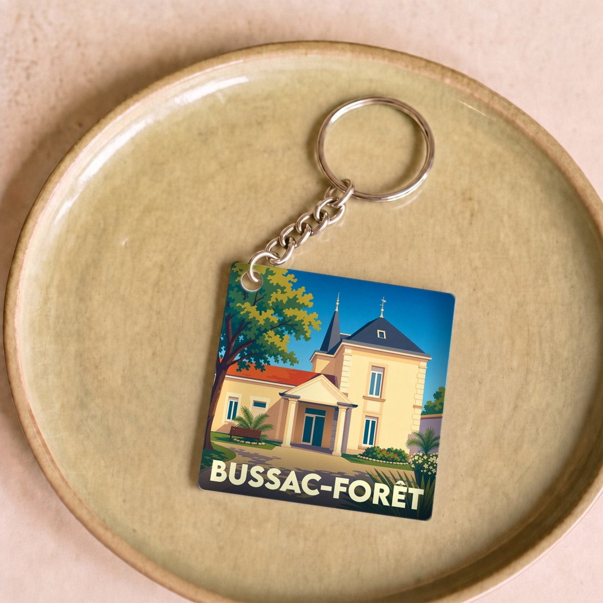 Porte-clés souvenir de la ville de Bussac-Forêt avec une illustration stylisée.