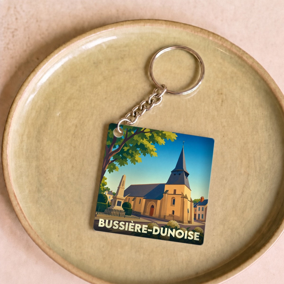 Porte-clés souvenir de la ville de Bussière-Dunoise avec une illustration stylisée.