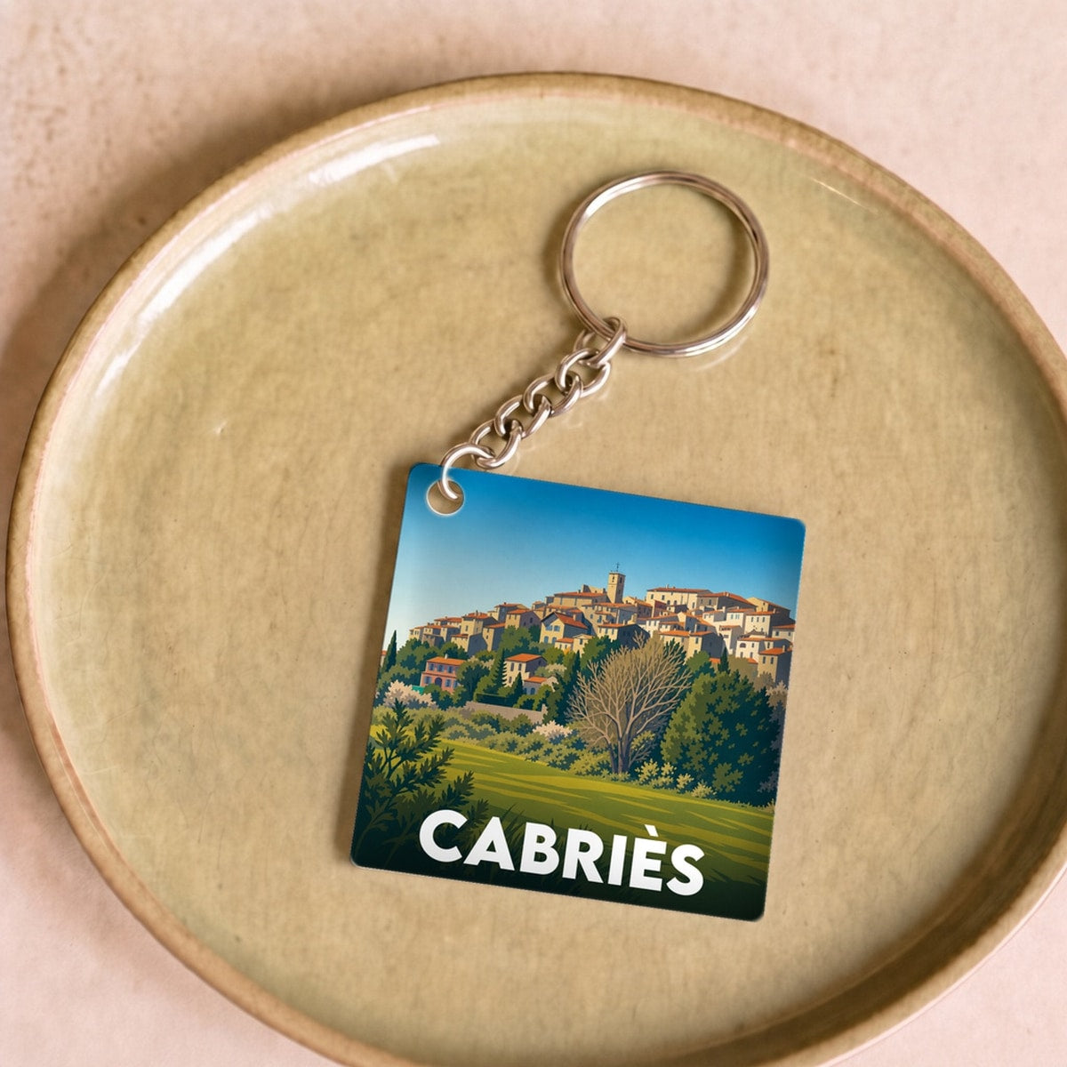 Porte-clés souvenir de la ville de Cabriès avec une illustration stylisée d'un village perché.