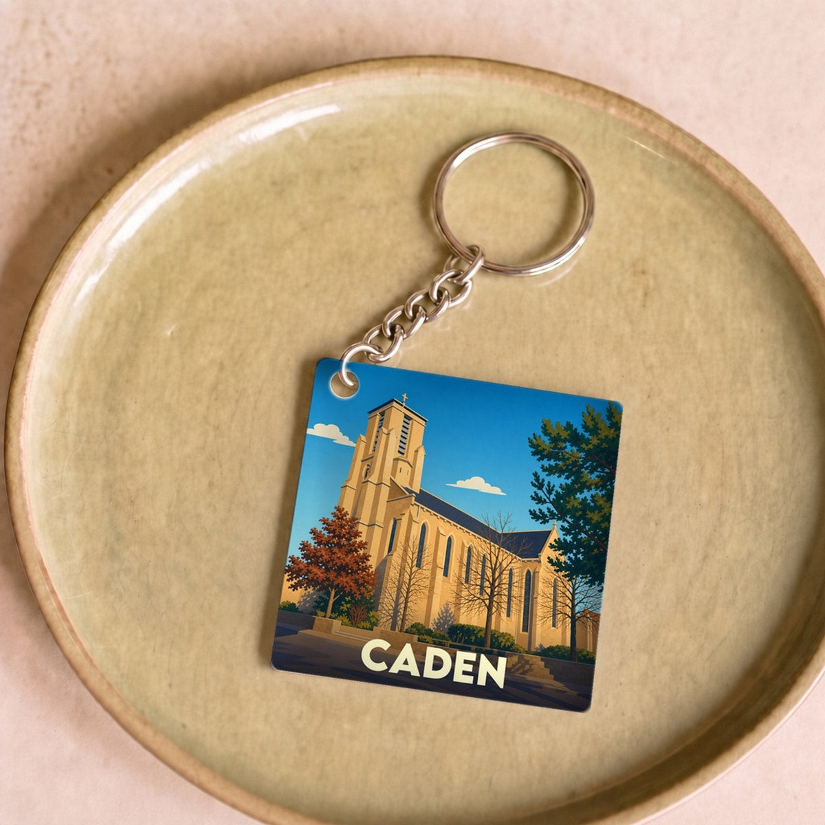 Porte-clés souvenir de la ville de Caden avec une illustration stylisée d'une église.