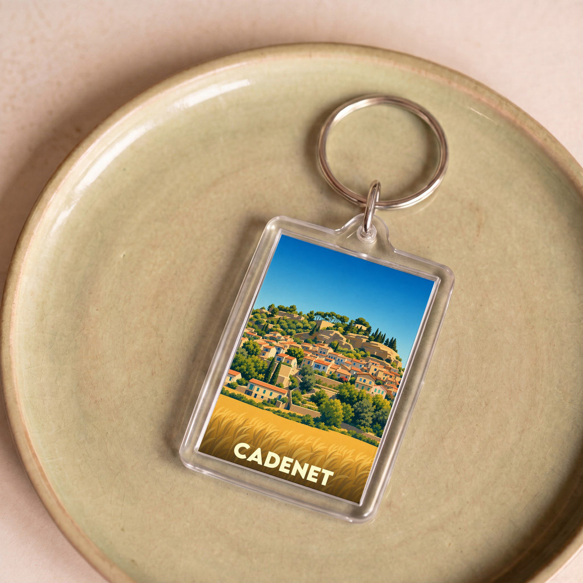 Porte-clés souvenir de la ville de Cadenet avec une illustration stylisée d'un village perché.