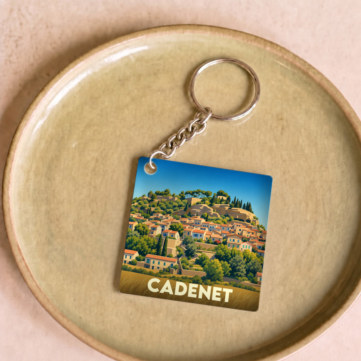 Porte-clés souvenir de la ville de Cadenet avec une illustration stylisée d'un village perché.